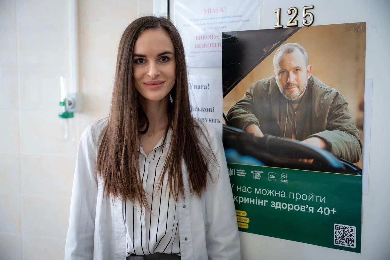 Лікарка КМКЛ №8 біля плаката програми «Скринінг здоров’я 40+»